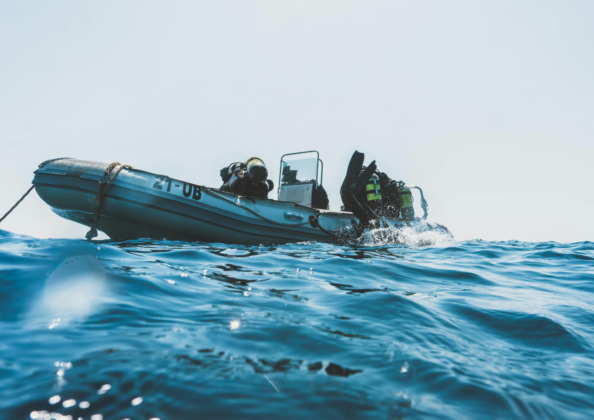 Bateau de plongée en mer avec plongeurs en équipement complet prêts à plonger, expérience nautique et aventure marine.