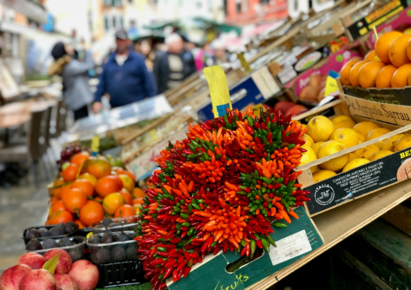 Étal de marché coloré avec piments rouges et verts, agrumes et fruits frais sur un marché traditionnel en Italie.